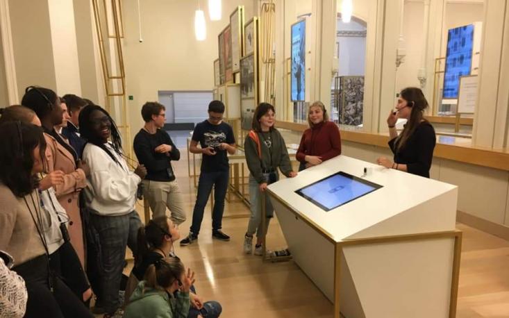 Groupe scolaire lors d'une visite guidée devant un écran interactif